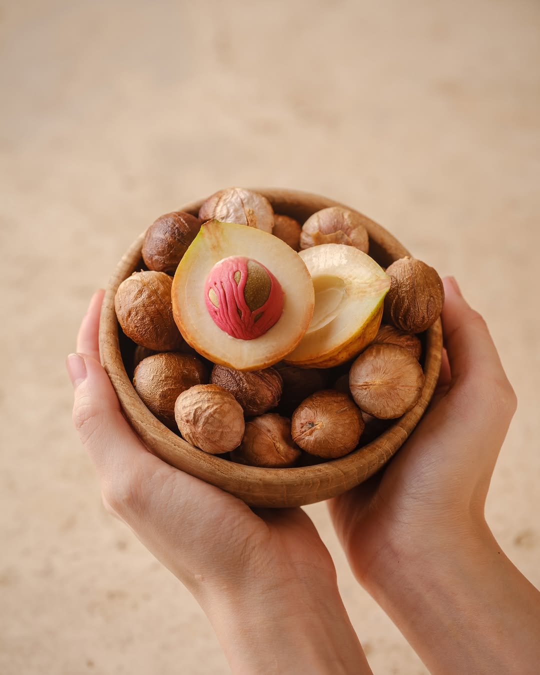 Fresh nutmeg fruit and nutmeg seeds in wooden bowl
